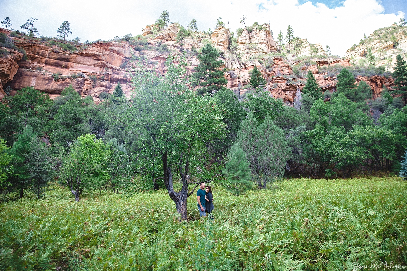 Couple in a field of ferns with red rock backdrop in Sedona