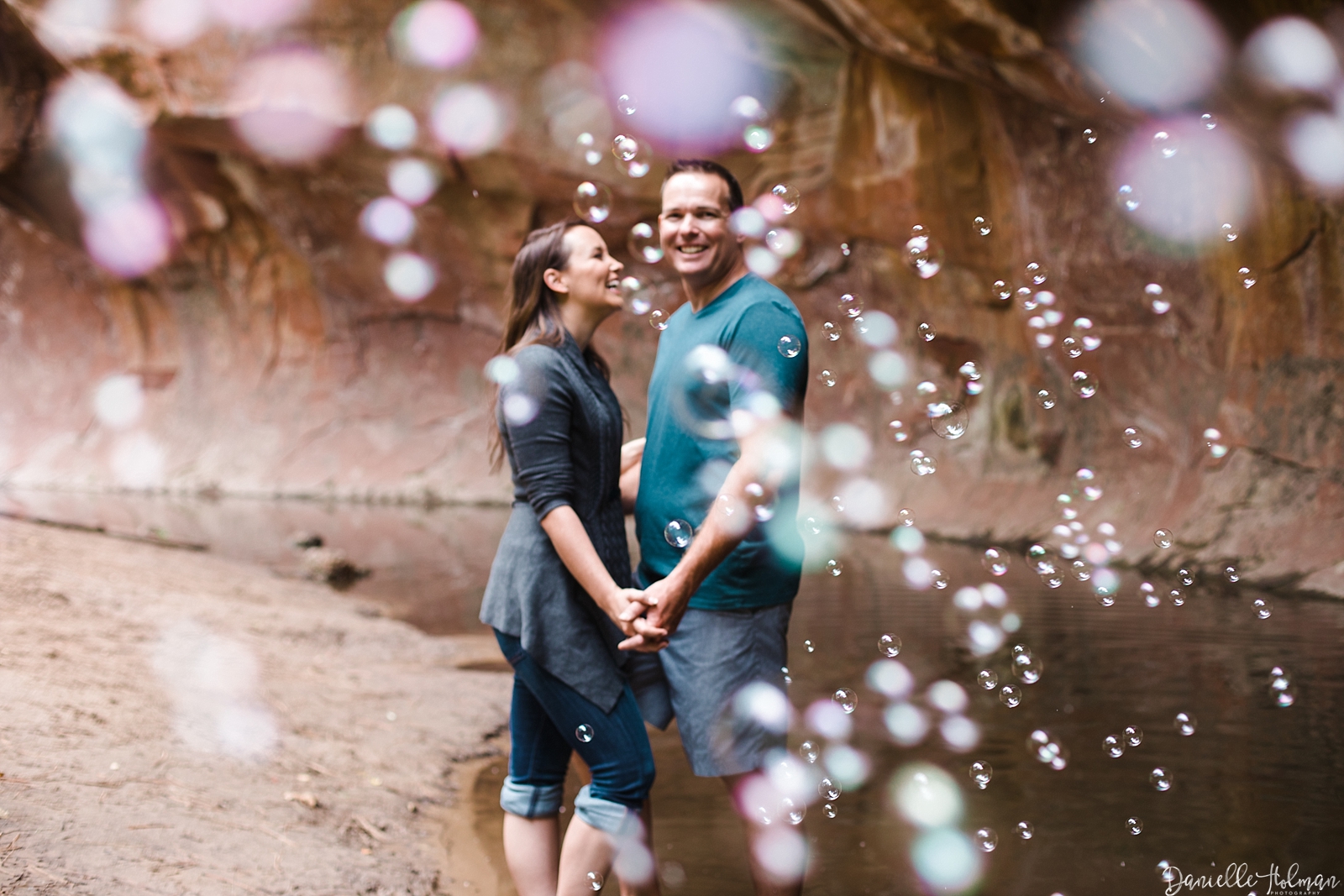 Blurred bubbles frame an engaged couple in the creek at West Fork Trail
