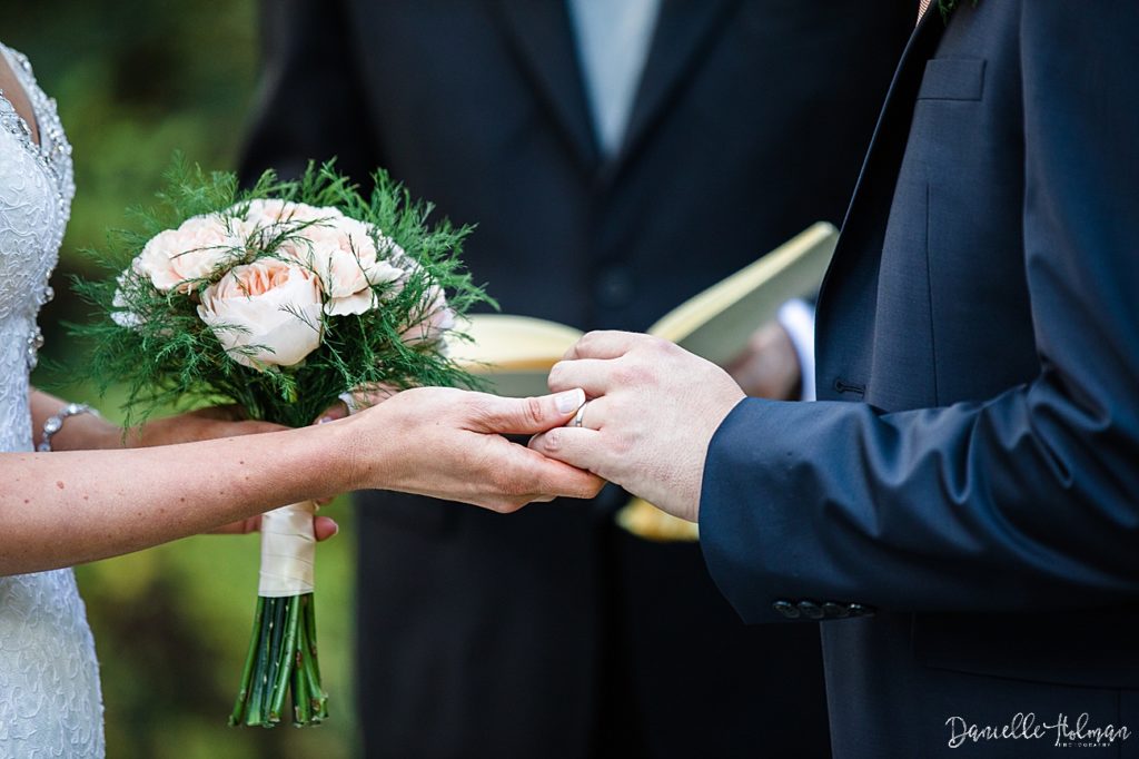 Close up of bride holding groom's hand and her boquet of flowers