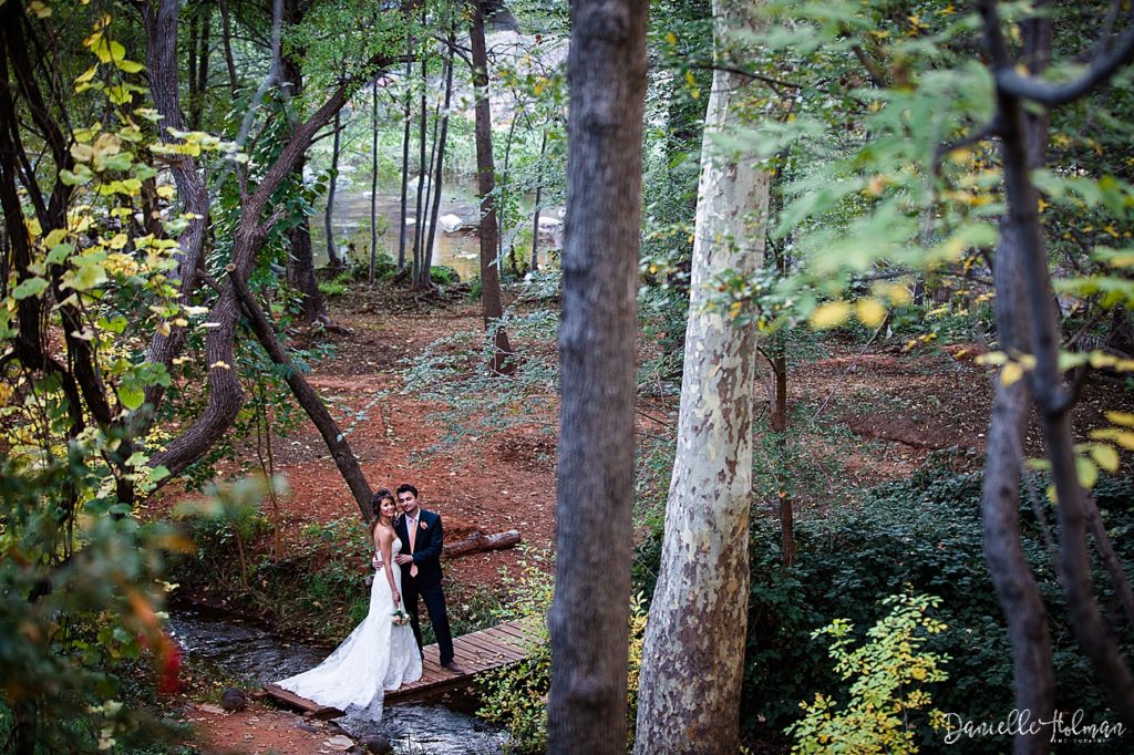 Sedona bride and groom standing on a bridge over a creek, with fall foliage