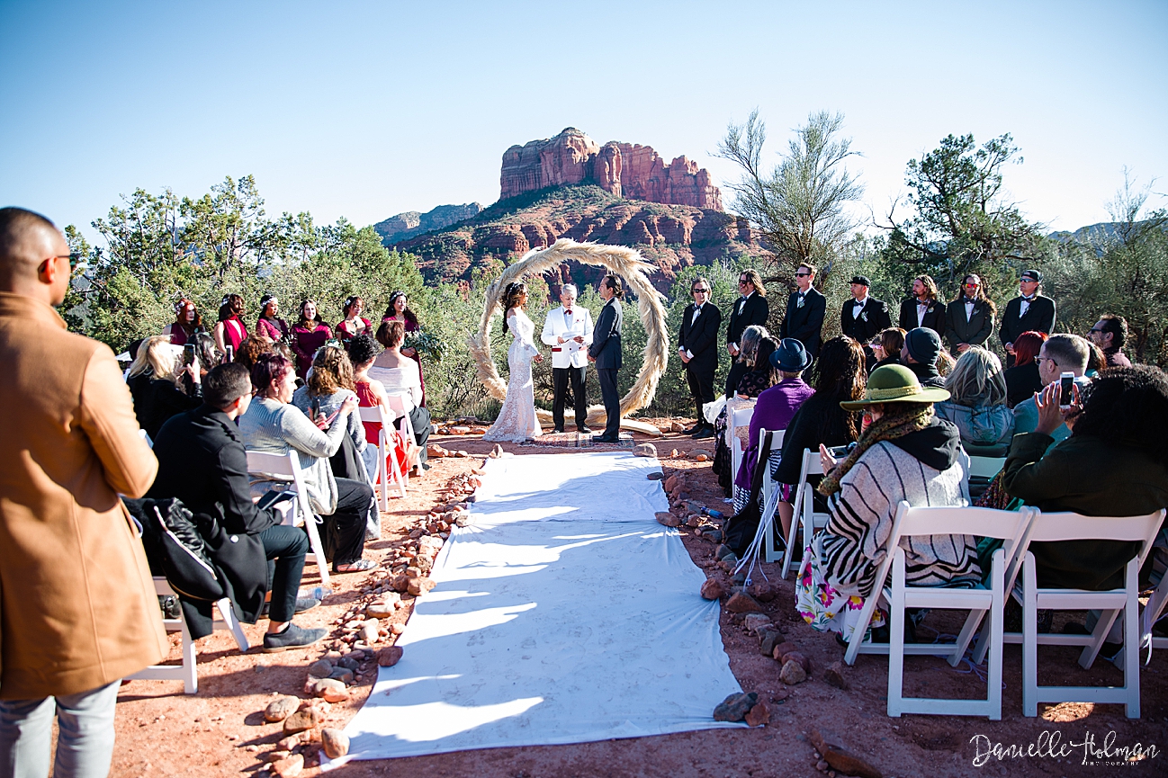 Overall scene of the ceremony with guests, arch, Bride, Groom and Sedona's Cathedral Rock